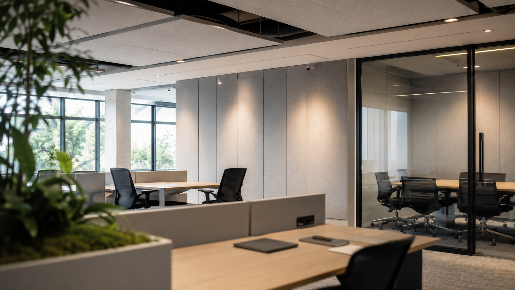 Open office with acoustic wall panels, ceiling clouds, and a glass meeting room